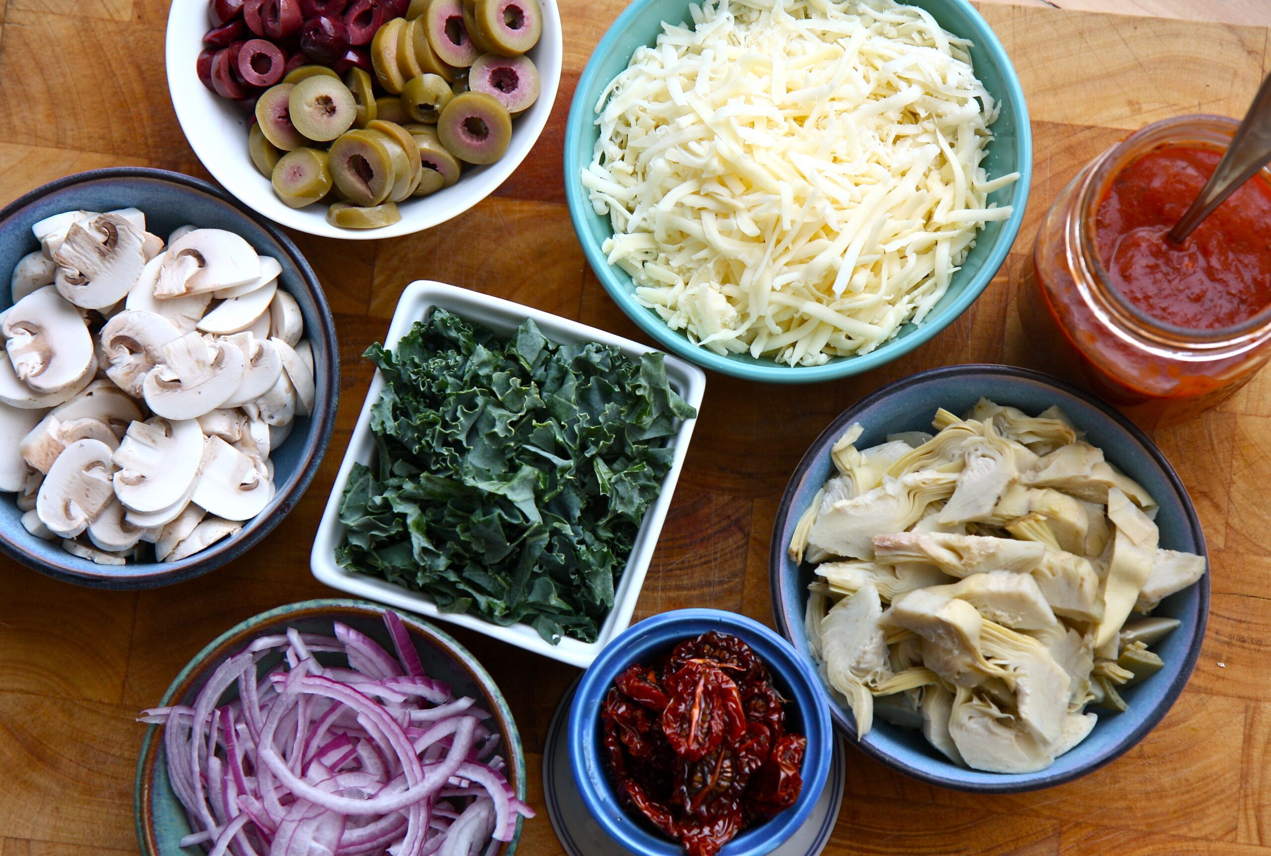 Vasious shaped bowls containging vegetables and other toppings for pizza